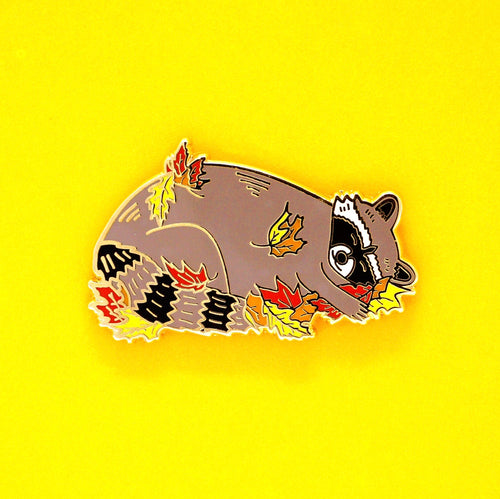 Sleeping raccoon in fall leaves enamel pin